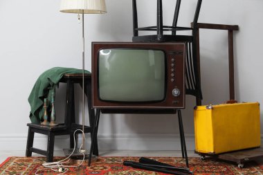 Retro TV tribünde, siyah sandalye, bavul ve lamba beyaz duvarın yanında. Kullanılmış eşyalar