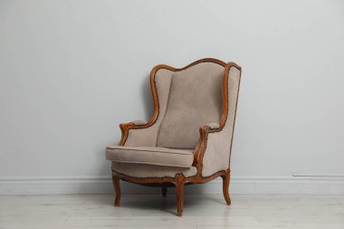 Açık gri duvarın yanındaki eski moda koltuk. Kullanılmış eşyalar