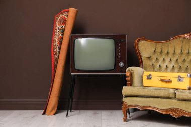 Retro TV stantta, kanepe, bavul ve halı kahverengi duvarın yanında. Kullanılmış eşyalar