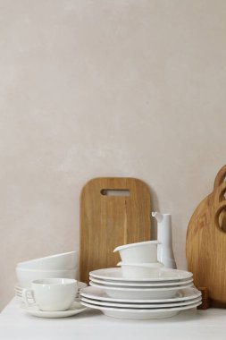 Mutfaktaki tezgahta farklı beyaz bulaşık takımları ve tahta kesme tahtaları var.