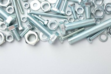 Beyaz arka planda metal cıvatalar ve fındıklar, düz yatış. Metin için boşluk