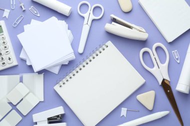 Beyaz not defteri ve mor arka planda diğer kırtasiye malzemesi, düz. Metin için boşluk