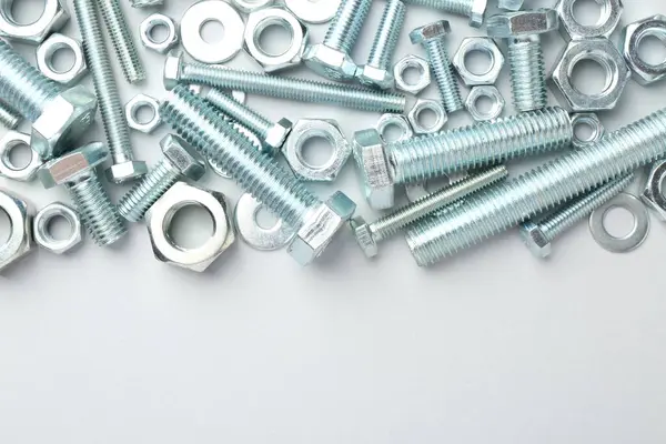 Beyaz arka planda metal cıvatalar ve fındıklar, düz yatış. Metin için boşluk