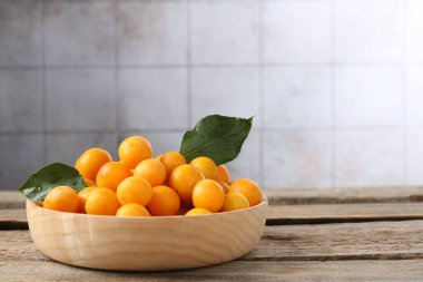 Olgun sarı kiraz erikleri ve ahşap masanın üzerindeki yapraklar. Metin için boşluk