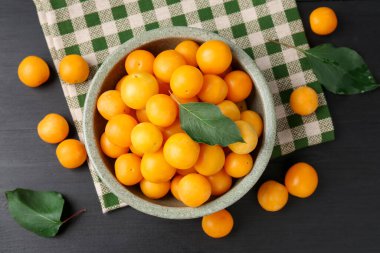 Olgun sarı kiraz erikleri, siyah ahşap masa üzerinde yapraklar, düz yatıyordu.