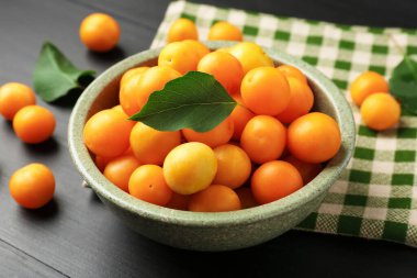 Olgun sarı kiraz erikleri Siyah ahşap masa üzerinde yapraklar, yakın çekim