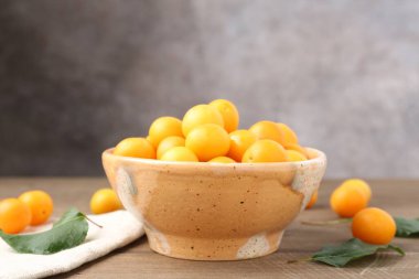 Olgun sarı kiraz erikleri ve yapraklar ahşap masada, yakın plan. Metin için boşluk