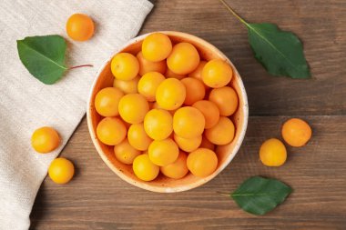 Olgun sarı kiraz erikleri ve yaprakları ahşap masada, düz yatıyordu.