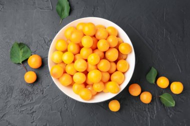 Olgun sarı kiraz erikleri ve yaprakları siyah masanın üzerinde, düz yatıyordu.