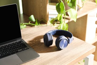 Laptop ve kablosuz kulaklıklar ahşap masa içinde.