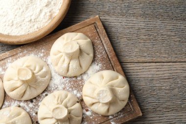 Ahşap masa üzerinde biber ve un ile pişirilmemiş khinkaliler (hamur köfteleri) düz yatıyordu. Metin için boşluk