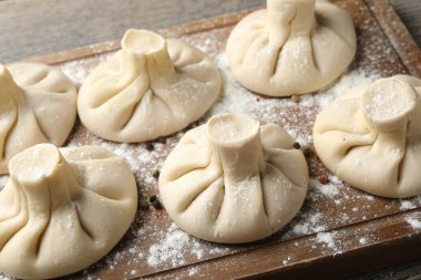 Ahşap masada pişmemiş khinkaliler (hamur tatlısı), yakın plan.