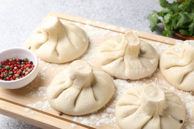 Pişmemiş khinkaliler (hamur tatlısı), biberler ve maydanozlar ışık masasında, yakın plan