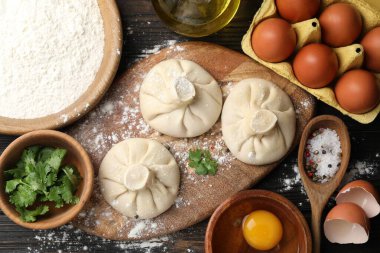 Ahşap masa üzerinde malzemelerle çevrili pişmemiş khinkaliler (hamur tatlısı)