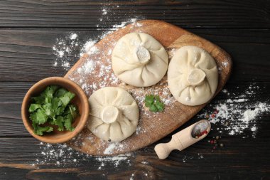 Pişmemiş khinkaliler (hamur tatlısı), baharatlar ve maydanozlar koyu ahşap masa üzerinde, düz yatıyordu.