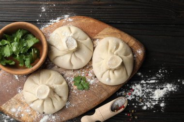 Pişmemiş khinkaliler (hamur tatlısı), baharatlar ve maydanozlar koyu ahşap masa üzerinde, düz yatıyordu.