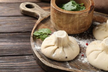 Ahşap masada biberli ve maydanozlu pişmemiş khinkaliler (hamur tatlısı), yakın plan.