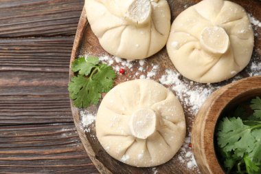 Ahşap masada pişmemiş khinkaliler (hamur tatlısı) ve maydanozlar.