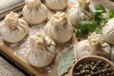 Biber, un ve defne yapraklarıyla pişirilmemiş khinkaliler (hamur köfteleri) ahşap masada, yakın plan