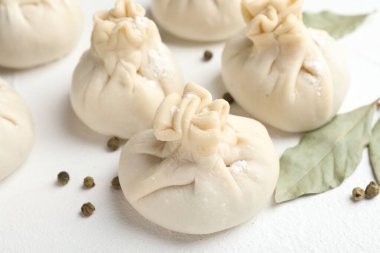 Biber ve defne yapraklarıyla pişirilmemiş khinkaliler (hamur tatlısı) beyaz masada, yakın plan.