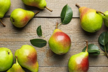 Taze armutlar ve ahşap masada yeşil yapraklar, düz uzanmış.