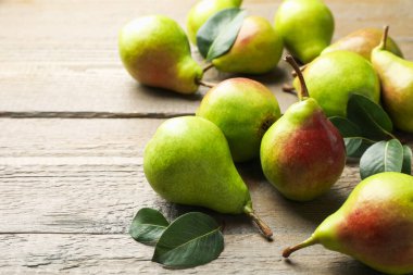 Taze armutlar ve ahşap masada yeşil yapraklar, yakın plan. Metin için boşluk