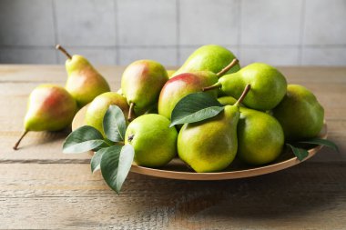 Taze armutlar ve ahşap masada yeşil yapraklar, yakın plan.