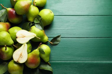 Taze olgun armutlar ve yeşil ahşap masa üzerinde yapraklar, düz. Metin için boşluk