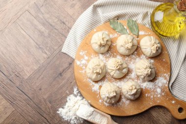 Ahşap masa üzerinde un, yağ ve defne yapraklarıyla pişirilmemiş khinkaliler (hamur tatlısı). Metin için boşluk