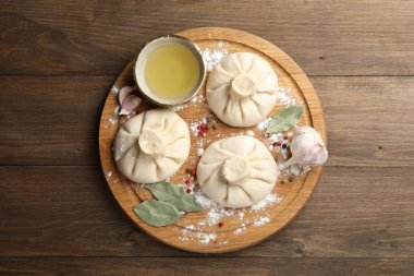 Biber, un ve defne yapraklarıyla ahşap masa üzerinde pişmemiş khinkaliler (hamur tatlısı)