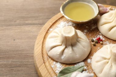 Biber, un ve defne yapraklarıyla pişirilmemiş khinkaliler (hamur köfteleri) ahşap masada, yakın plan. Metin için boşluk