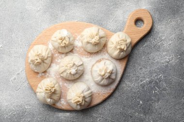 Gri masa üzerinde un bulunan pişmemiş khinkaliler (hamur tatlısı), üst görünüm