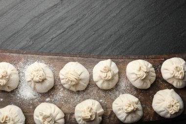 Siyah masa üzerinde un bulunan pişmemiş khinkaliler (hamur tatlısı). Metin için boşluk