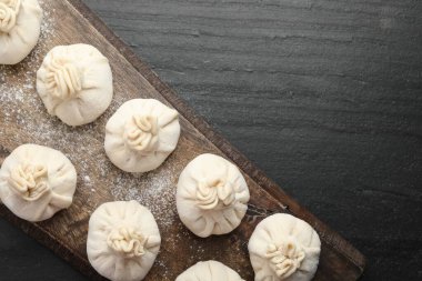 Siyah masa üzerinde un bulunan pişmemiş khinkaliler (hamur tatlısı). Metin için boşluk