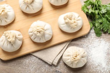 Tahta masada pişmemiş khinkalis (hamur tatlısı) ve kişniş, düz konum