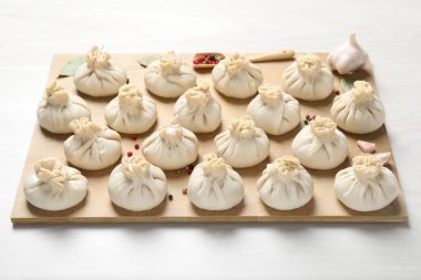 Pişmemiş khinkaliler (hamur tatlısı) ve beyaz ahşap masa üzerindeki baharatlar, yakın plan.