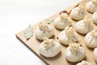 Pişmemiş khinkaliler (hamur tatlısı) ve beyaz ahşap masa üzerindeki baharatlar, yakın plan.