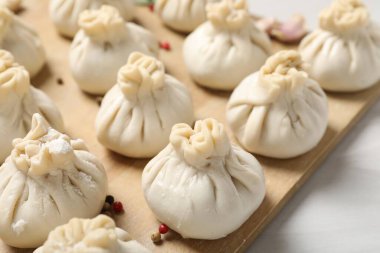 Beyaz masada pişmemiş khinkaliler (hamur tatlısı) ve baharatlar, yakın plan.