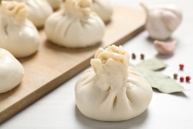 Pişmemiş khinkaliler (hamur tatlısı) ve beyaz ahşap masa üzerindeki baharatlar, yakın plan.