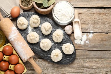 Pişmemiş khinkaliler (hamur köfteleri), un, baharatlar, yumurtalar ve tahta masa üzerinde merdane. Metin için boşluk