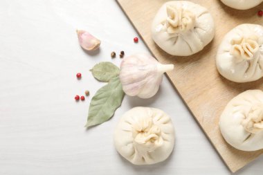 Pişmemiş khinkaliler (hamur tatlısı) ve beyaz ahşap masa üzerindeki baharatlar, düz yatış. Metin için boşluk