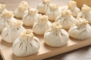 Ahşap masada pişmemiş khinkaliler (hamur tatlısı), yakın plan.