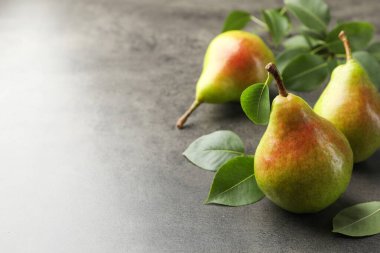 Taze armutlar ve yeşil yapraklar gri masada, yakın plan. Metin için boşluk