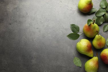 Taze armutlar ve yeşil yapraklar gri masada, düz yerde. Metin için boşluk