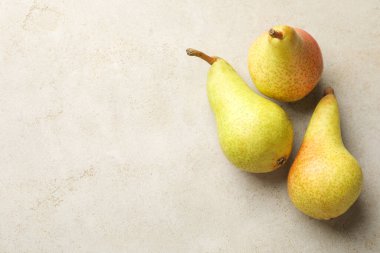 Açık gri masada taze olgun armutlar, düz uzanmış. Metin için boşluk