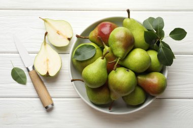 Taze armutlar, bıçak ve yeşil yapraklar beyaz ahşap masada, düz yatıyordu.