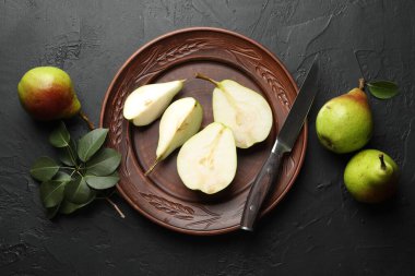 Taze armutlar, bıçak ve yeşil yapraklar siyah masada, düz yerde.