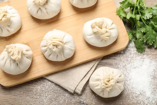 Tahta masada pişmemiş khinkalis (hamur tatlısı) ve kişniş, düz konum