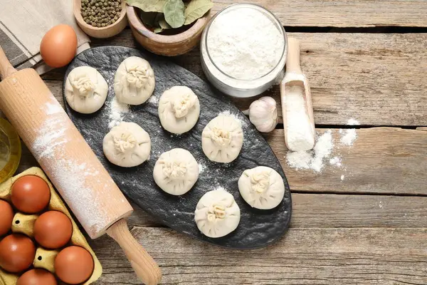 Pişmemiş khinkaliler (hamur köfteleri), un, baharatlar, yumurtalar ve tahta masa üzerinde merdane. Metin için boşluk