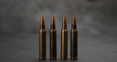 Gri masadaki ateşli silah fişekleri dumana karşı, yakın plan.